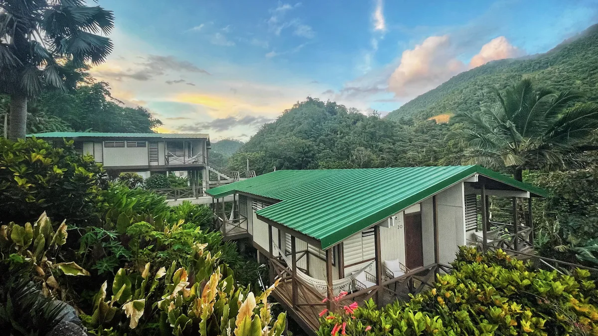 Green-roofed guest buildings surrounded by mountains and tropical vegetation at Casa Grande Mountain Retreat.