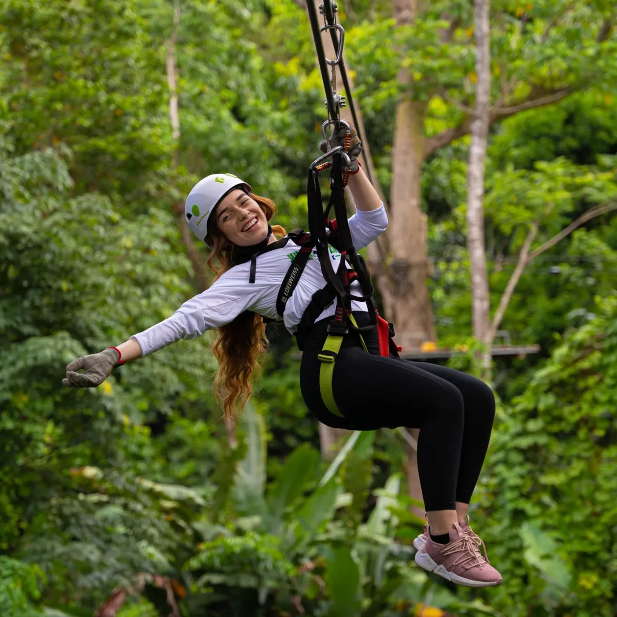 A helmeted guest riding a zipline through the forest at JungleQui.